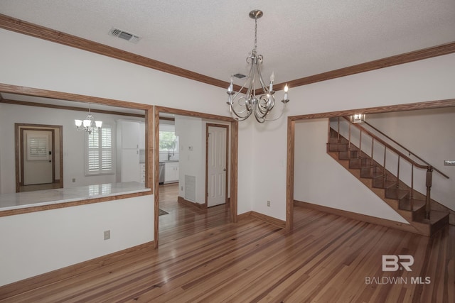 interior space featuring ornamental molding, hardwood / wood-style floors, a textured ceiling, and a notable chandelier