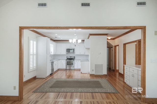 kitchen with pendant lighting, white cabinetry, stainless steel appliances, an inviting chandelier, and light hardwood / wood-style flooring