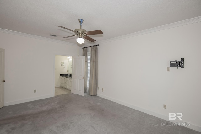 empty room featuring crown molding, light colored carpet, ceiling fan, and a textured ceiling