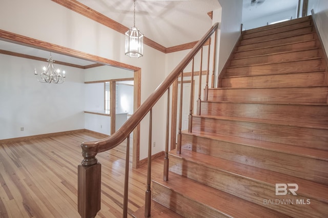 stairway featuring crown molding, hardwood / wood-style floors, and an inviting chandelier