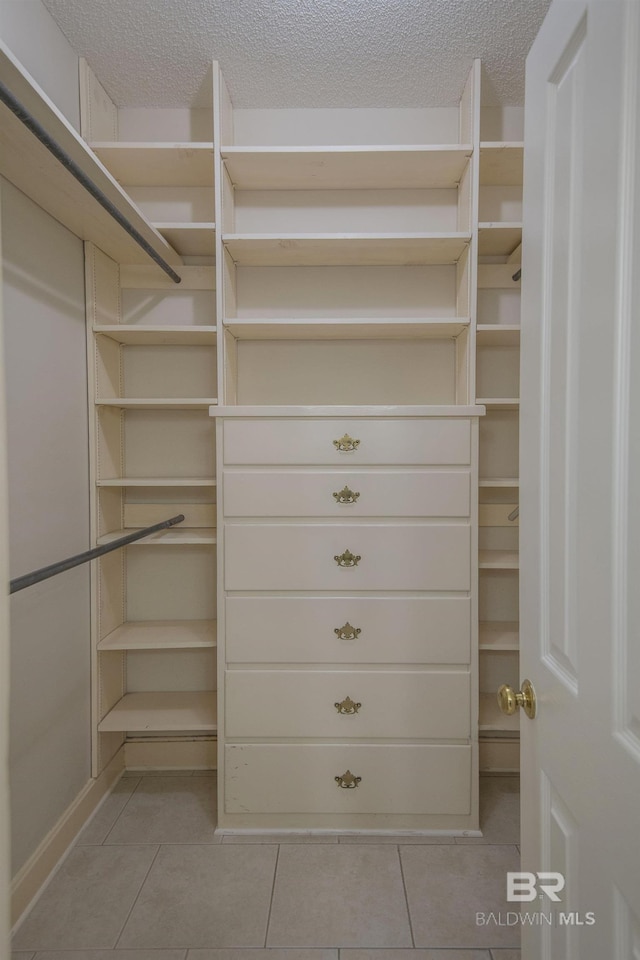 walk in closet with light tile patterned floors