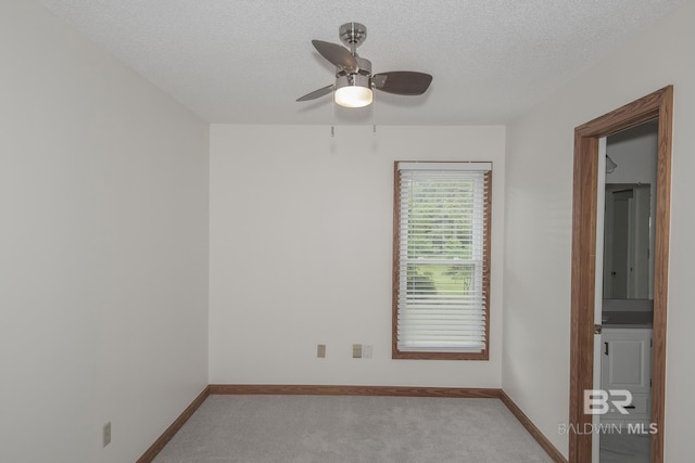 unfurnished room featuring ceiling fan, light colored carpet, and a textured ceiling