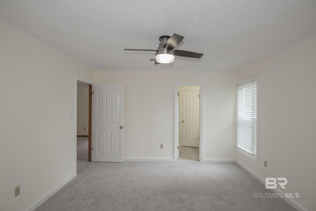 unfurnished room with ceiling fan, light carpet, and a textured ceiling