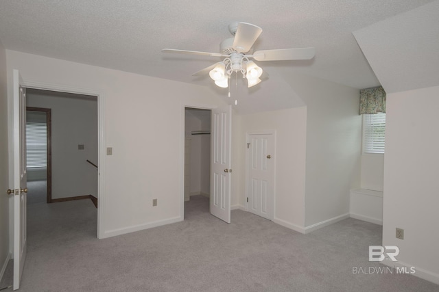 unfurnished bedroom featuring ceiling fan, light colored carpet, a closet, and a textured ceiling