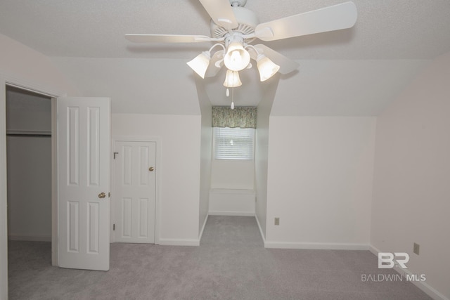 unfurnished bedroom featuring lofted ceiling, a spacious closet, light colored carpet, and a textured ceiling