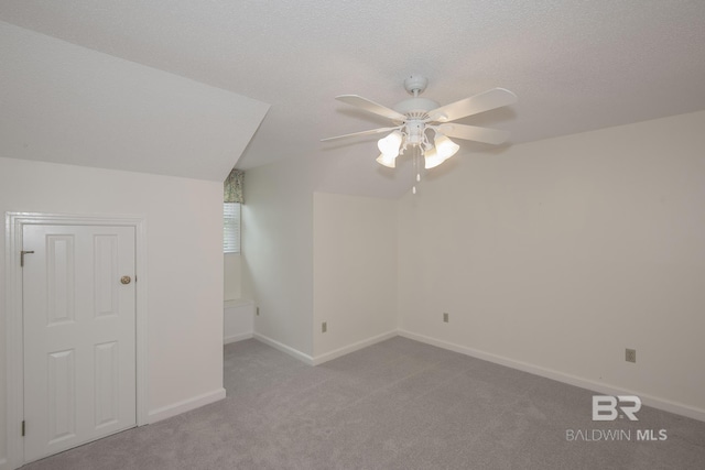 additional living space with ceiling fan, light colored carpet, and a textured ceiling