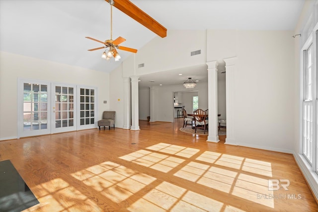 unfurnished living room featuring ornate columns, hardwood / wood-style floors, beamed ceiling, and ceiling fan with notable chandelier