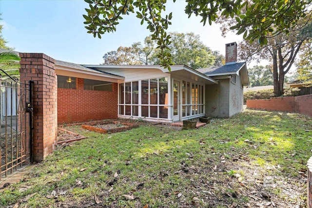 rear view of house with a yard and a sunroom