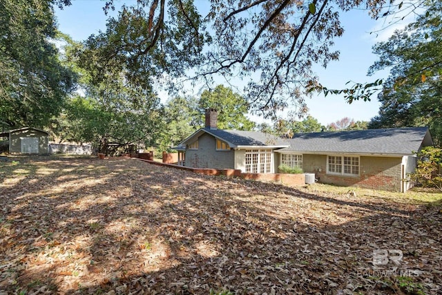 rear view of house with a storage shed and central air condition unit