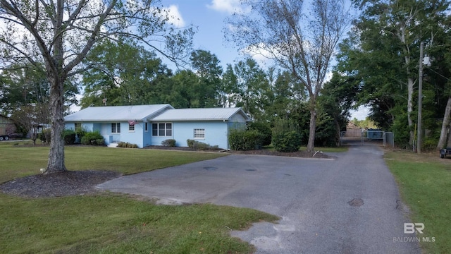 ranch-style home with metal roof, aphalt driveway, a front lawn, and a gate