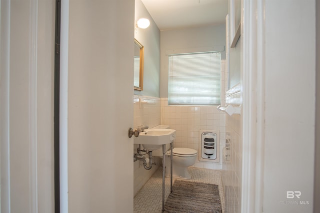 half bathroom featuring a wainscoted wall, tile walls, heating unit, toilet, and tile patterned floors