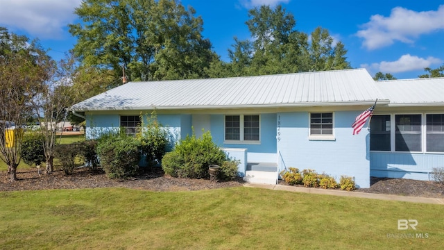 ranch-style house with metal roof, brick siding, and a front yard