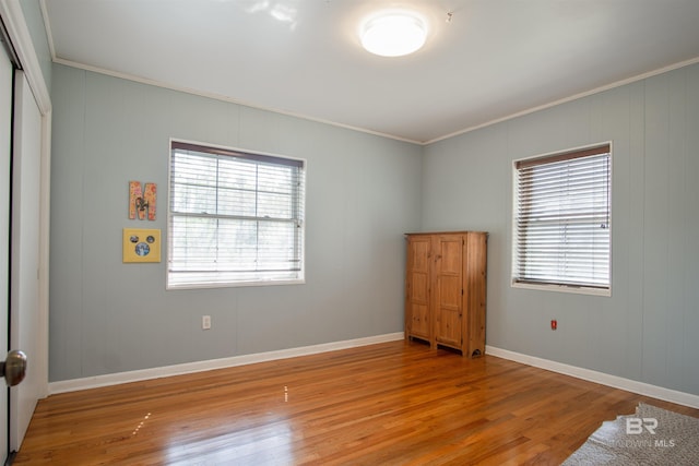 unfurnished bedroom with light wood-style flooring, baseboards, and ornamental molding