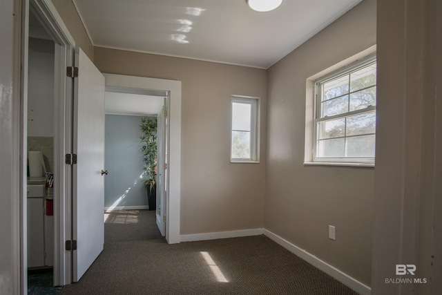 interior space featuring dark carpet and baseboards