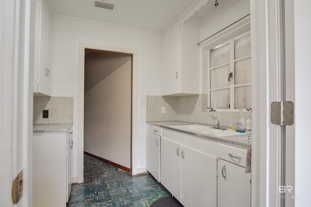 kitchen with white cabinets, visible vents, light countertops, and a sink