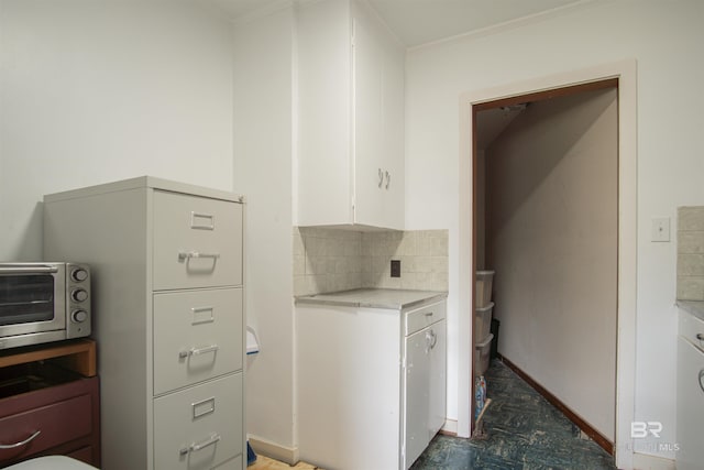 laundry room featuring crown molding, baseboards, and a toaster