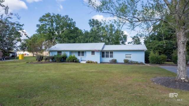 single story home featuring a front yard, metal roof, and stucco siding