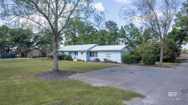 ranch-style home with driveway, metal roof, and a front lawn