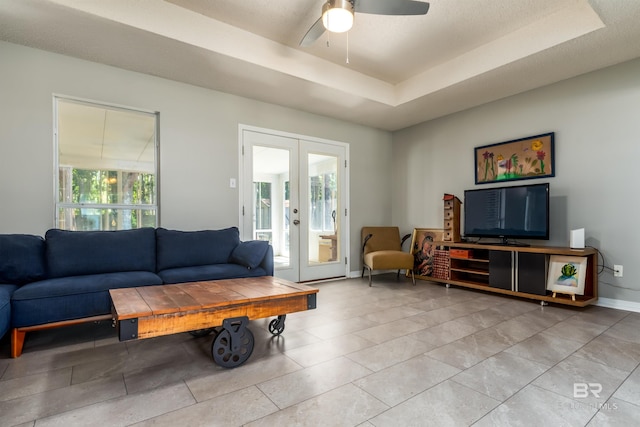 living room featuring a tray ceiling, french doors, and a healthy amount of sunlight