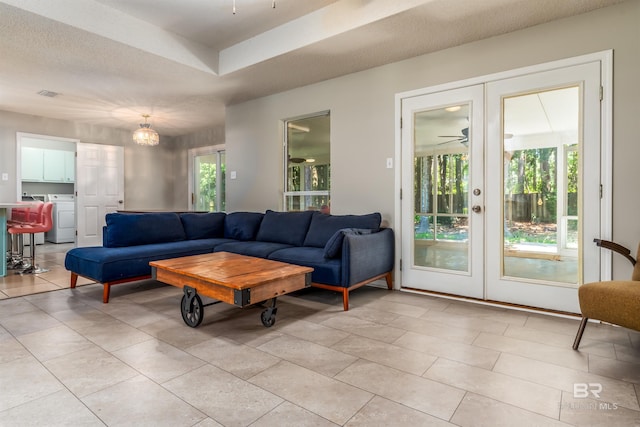 living room featuring french doors, ceiling fan, washer / dryer, and a textured ceiling