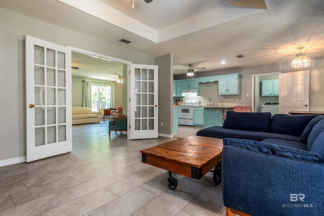 living room featuring washer / dryer, a textured ceiling, ceiling fan, and french doors