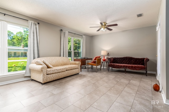 tiled living room with ceiling fan and a textured ceiling