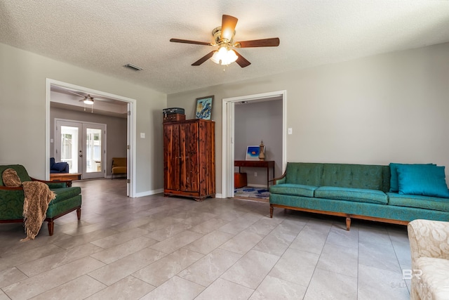 living room with ceiling fan, a textured ceiling, and french doors