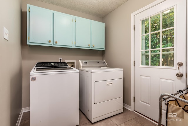 laundry room featuring cabinets, washing machine and dryer, a textured ceiling, and light tile patterned floors