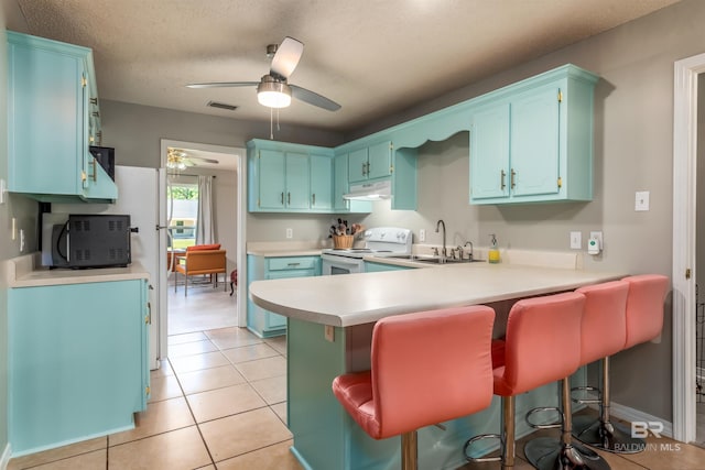 kitchen with sink, white range with electric cooktop, a kitchen breakfast bar, light tile patterned flooring, and kitchen peninsula