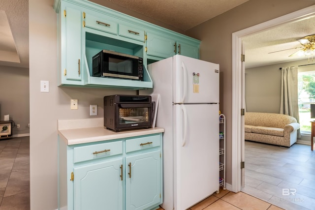 kitchen with ceiling fan, light tile patterned floors, white fridge, and a textured ceiling