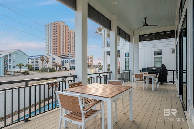 wooden deck with a view of city, ceiling fan, and grilling area