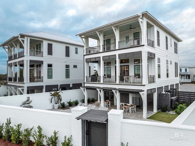 view of front of house featuring a balcony, a patio area, a fenced backyard, and board and batten siding