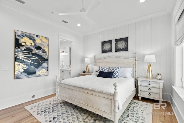 bedroom with crown molding, visible vents, ensuite bath, wood finished floors, and baseboards