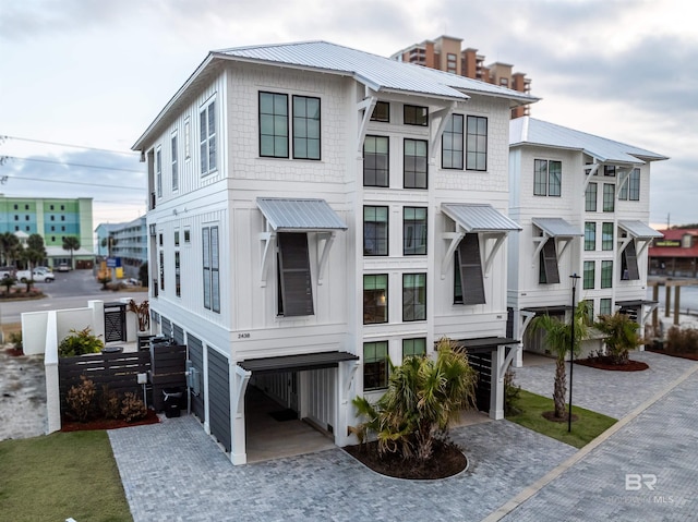 coastal inspired home with metal roof, a carport, and decorative driveway