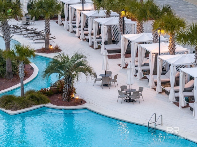 community pool with a patio and outdoor dining area