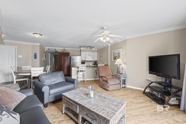 living room featuring light wood-style flooring, baseboards, a ceiling fan, and ornamental molding