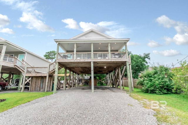 raised beach house with a front yard, a carport, and a porch