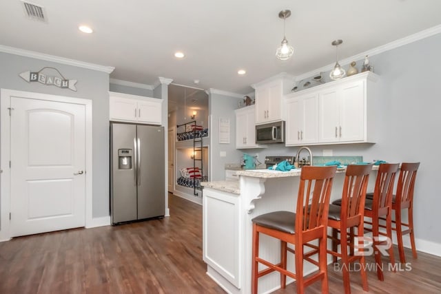 kitchen featuring pendant lighting, dark wood-type flooring, stainless steel appliances, a kitchen breakfast bar, and white cabinets