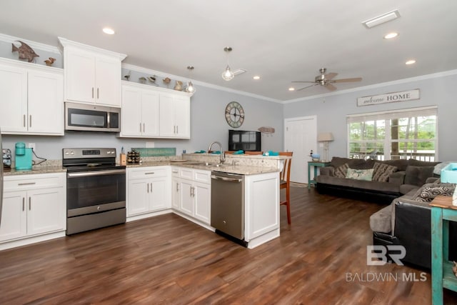 kitchen with light stone countertops, stainless steel appliances, kitchen peninsula, and white cabinets