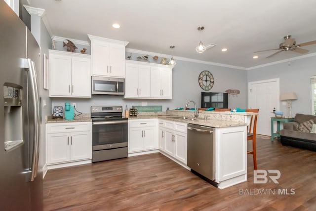 kitchen featuring white cabinetry, appliances with stainless steel finishes, decorative light fixtures, and kitchen peninsula