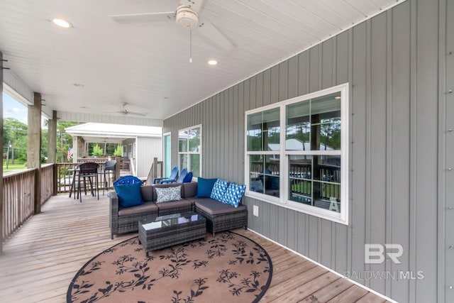 wooden deck featuring an outdoor living space, ceiling fan, and exterior bar