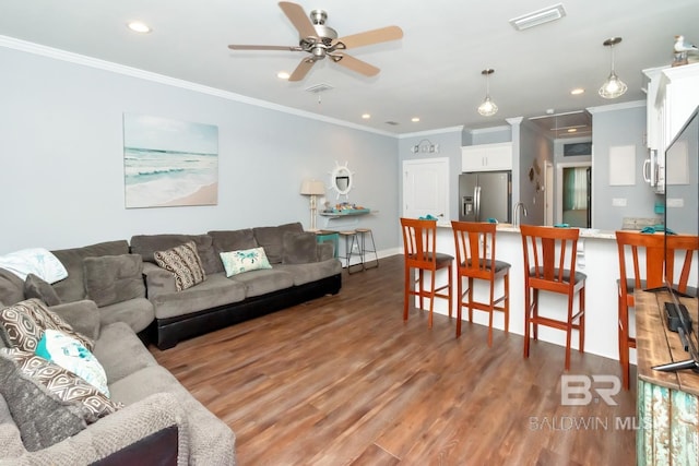 living room featuring hardwood / wood-style floors, crown molding, sink, and ceiling fan