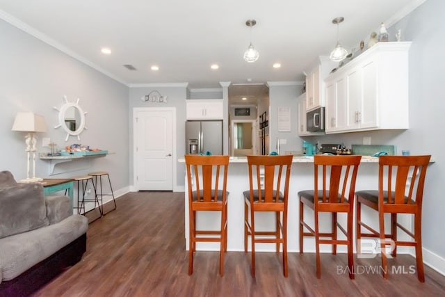 kitchen with dark hardwood / wood-style floors, stainless steel appliances, a breakfast bar, and white cabinets