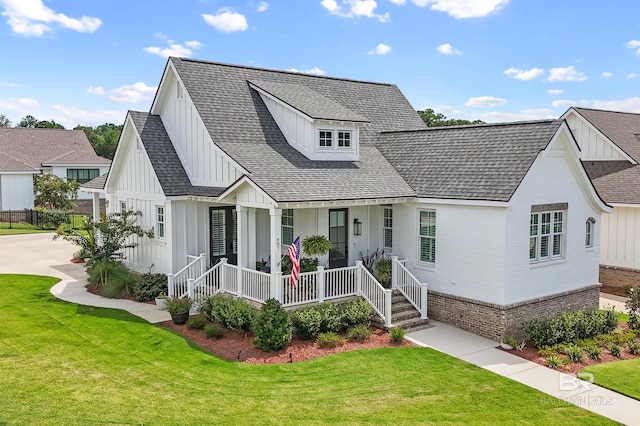887 Geranium Dr, Fairhope, AL 36532 - modern farmhouse style home featuring board and batten siding, covered porch, a front yard, brick siding, and a shingled roof