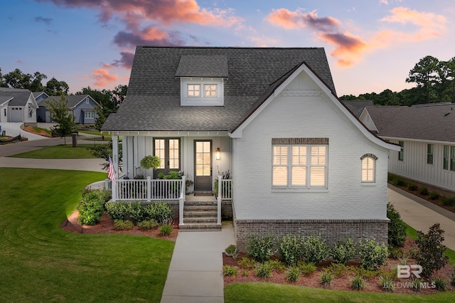 887 Geranium Dr, Fairhope, AL 36532 - view of front of home with a porch, brick siding, a front yard, and a shingled roof