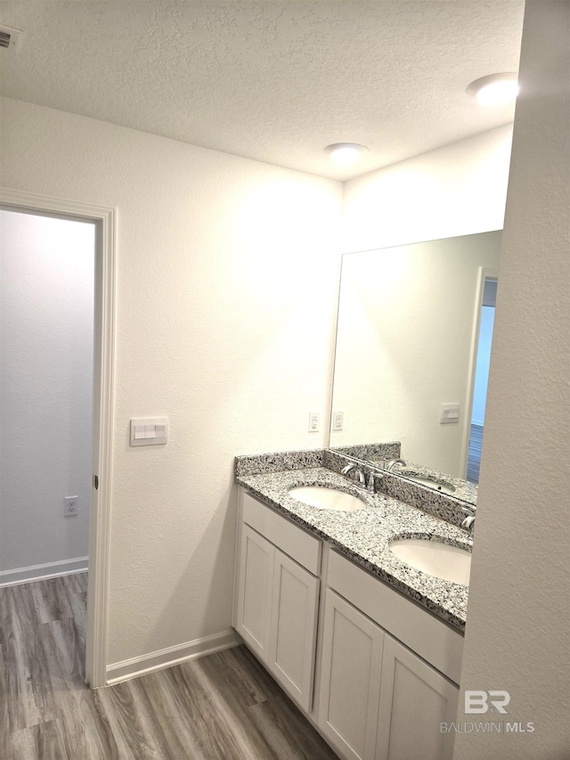 bathroom with vanity, wood-type flooring, and a textured ceiling