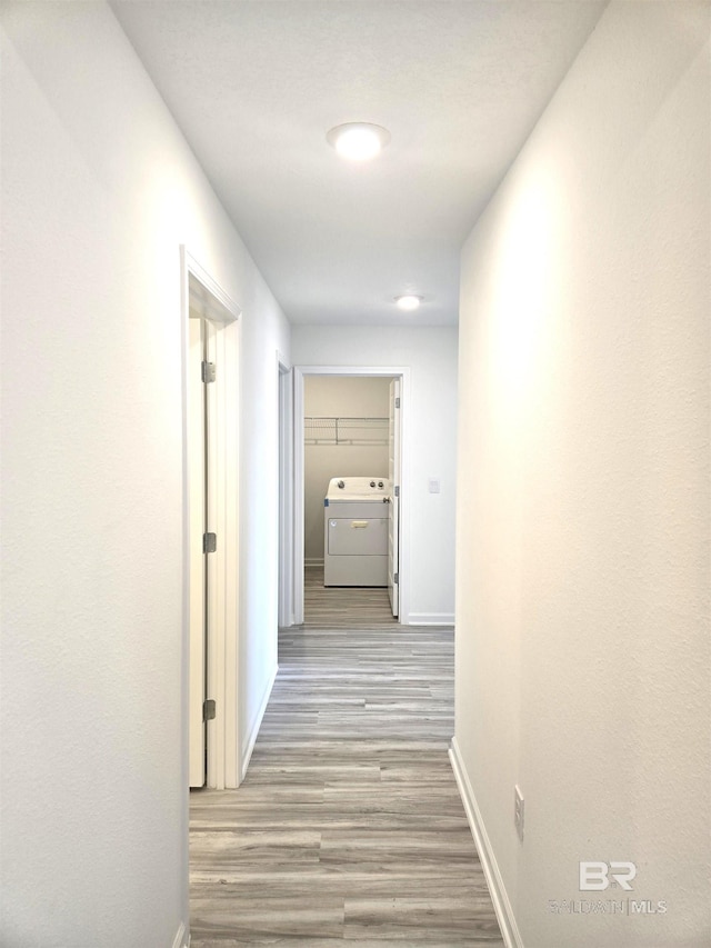 hallway with washer / clothes dryer and light hardwood / wood-style floors