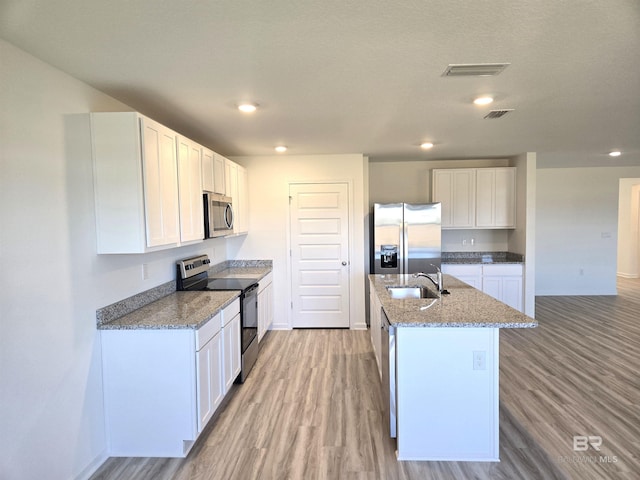 kitchen with sink, stainless steel appliances, light stone countertops, a kitchen island with sink, and white cabinets