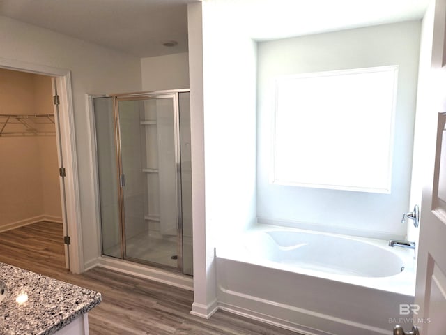 bathroom with independent shower and bath, vanity, and hardwood / wood-style floors