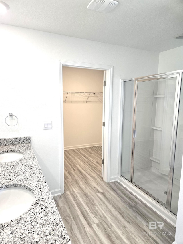 bathroom featuring wood-type flooring, a shower with shower door, and a textured ceiling